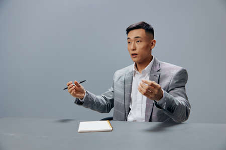Asian man in a gray suit in the office with a notepad on the table the idea of writing Lifestyle