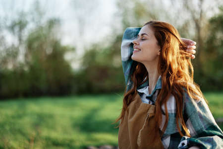 Close-up portrait of the face of a smiling, beautiful redheaded young woman in nature in a green...