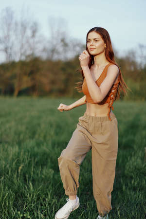 A woman of athletic build runs through the park on the green grass with loose, flying hair and...