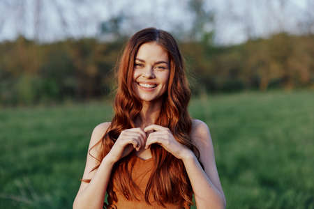 Funny young beautiful woman curves in front of the camera lounging in nature in the sunlightの写真素材