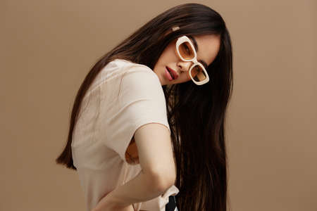 pretty woman attractive look charmin dark glasses in a t-shirt beige background
