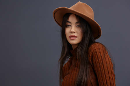 Brunette brown hat hand gestures brown sweater fashion emotions Gray background