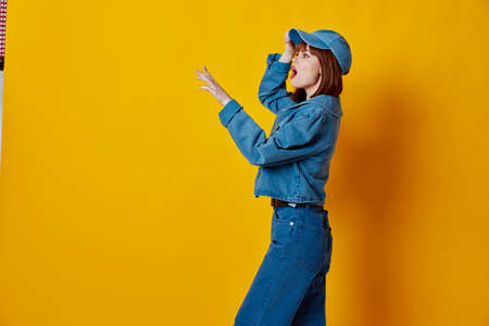 Positive young woman stylish denim clothing posing yellow background unalteredの写真素材