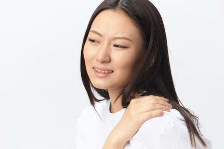 Suffering from neuralgia after sleeping in wrong position tanned beautiful young Asian woman...