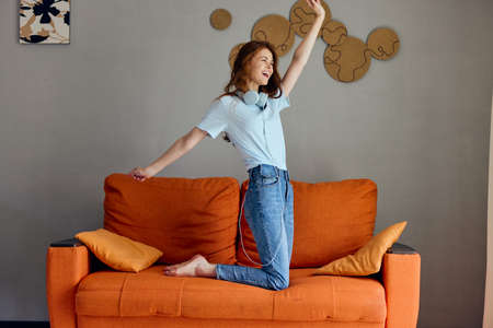 pretty woman listening to music with headphones on the orange sofa technologies