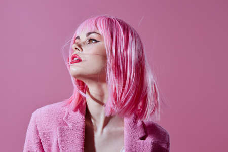 Pretty young female pink jacket holding hair cosmetics color background unalteredの写真素材