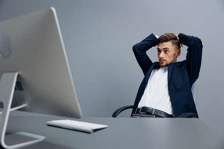 handsome businessman sitting at a desk in front of a computer Gray background