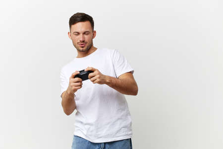 Passionate happy tanned handsome man in basic t-shirt play active online game with joystick gamepad...