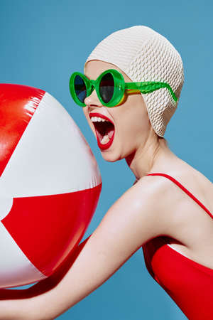 A screaming, agitated swimmer with red ball for swimming yells to the side on a blue background. Conceptual art of the new generationの写真素材