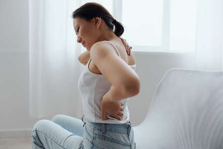 Suffering from scoliosis osteochondrosis after long study pretty young Asian woman feel hurt joint...