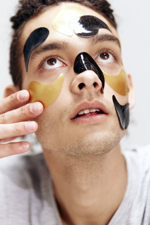 handsome guy black and gold patches on the face health cosmetology isolated background