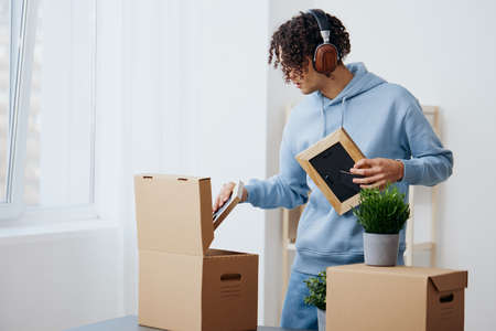 portrait of a man cardboard boxes in the room unpacking in headphones sorting things outの写真素材