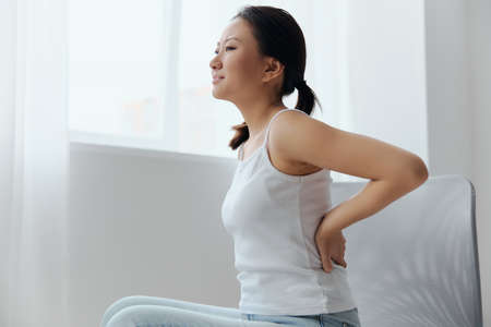 Suffering from scoliosis osteochondrosis after long study pretty young Asian woman feel hurt joint...
