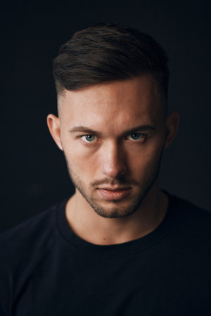 Modelling snapshots. Evil self-confident tanned attractive handsome man in classic suit jacket looks at camera posing isolated in black studio background. Fashion offer. Copy space for ad. Closeupの写真素材