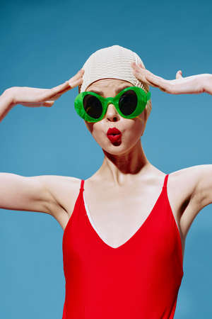 Surprised, shocked, a strange swimmer in glasses touches her head posing on a blue background. Art...