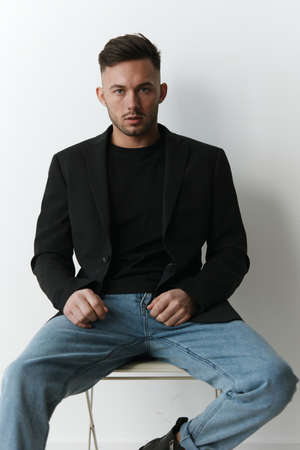 Modelling snapshots. Serious narcissistic self-confident attractive handsome man in classic suit sit on chair posing isolated in white studio background. Fashion offer. Copy space for adの写真素材