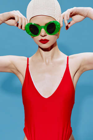 A swimmer in a white cap and a red swimsuit puts on strange glasses in the studioの写真素材