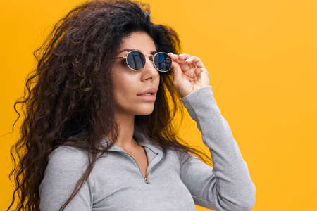 COOL OFFER. Portrait of successful attractive Latin female with afro in sunglasses, look at ampty...