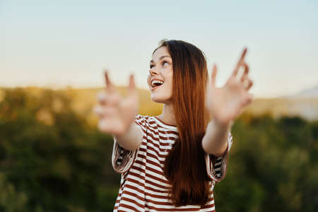 A woman smiles and pulls her hands to the camera close-up in nature with a view of the mountains....