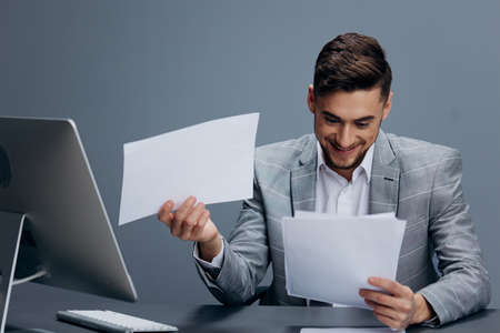 manager in a gray suit sits in front of a computer executive