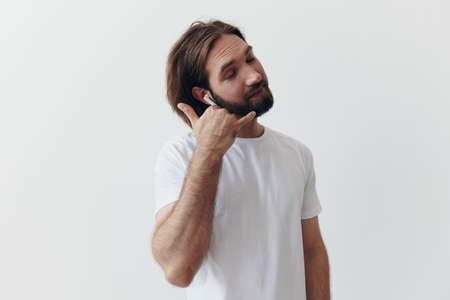 happy man listening to music and smiling in a white t-shirt on a white background happy