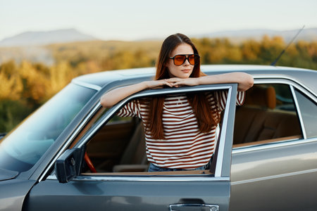 A young woman driver looks out of the car at the autumn landscape and smiles satisfactorily