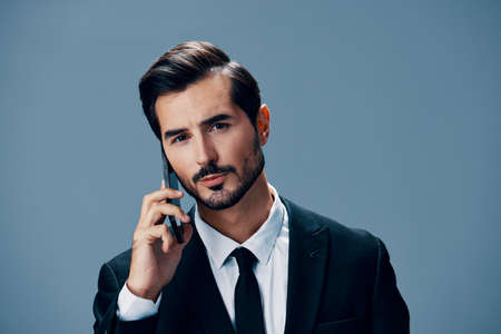 Portrait of business man with phone conversation and on blue background in business suit. Business...
