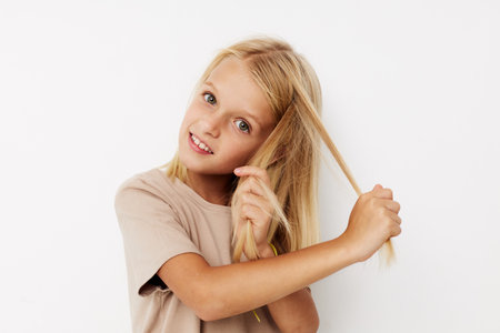 Beautiful little girl beige t-shirts grimace posing studioの写真素材