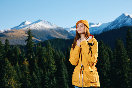 Woman with red hair hiker standing on the mountain hands up happiness overlooking snowy mountains...