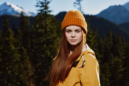 Young woman tourist portrait in yellow raincoat traveling and hiking in the mountains. Hiking in...