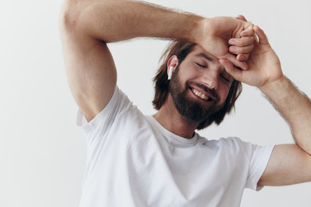 Stylish man in a white t-shirt with wireless headphones in his ears having fun listening to music smile on a white background lifestyleの写真素材