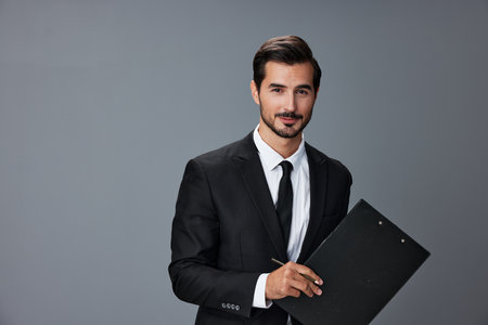 Portrait of a business man in a stylish suit smile with teeth hands up handsome face on gray isolated background with tablet in hand. Business concept young businessman startup copy space.の写真素材