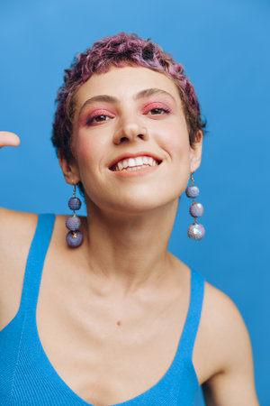 Young athletic fashion woman with colored hair and short haircut posing and dancing in blue...