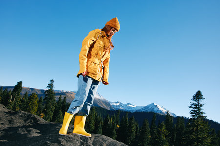 Woman with red hair hiker jumping on mountain hands up happiness overlooking snowy mountains in...