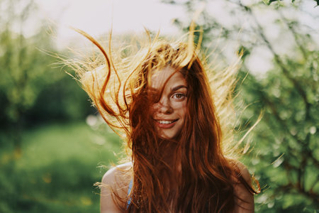 Woman portrait smile happiness catch looks into the camera with a smile with teeth spring flying hair long red, the concept of health and beauty hair sunsetの写真素材