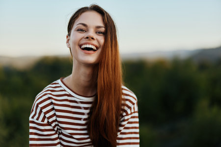 Young woman in a striped t-shirt smiles cutely on a journey against the backdrop of autumn natureの写真素材