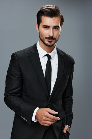 Stylish young man in a brunette business suit posing on a gray background and smiling businessmanの写真素材
