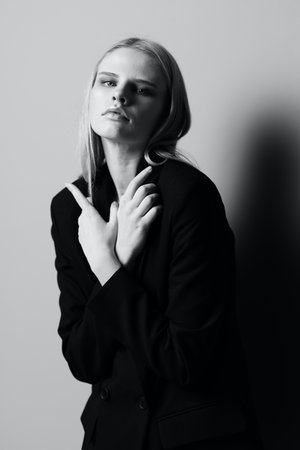 A stylish professional model crosses her arms on her chest and holds a jacket while posing in the studio. Fashionable stylish photo. Concept for clothing brandsの写真素材
