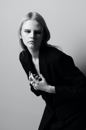 A stylish woman holds a jacket collar while posing in the studio. Fashionable stylish photo. Concept for clothing brandsの写真素材