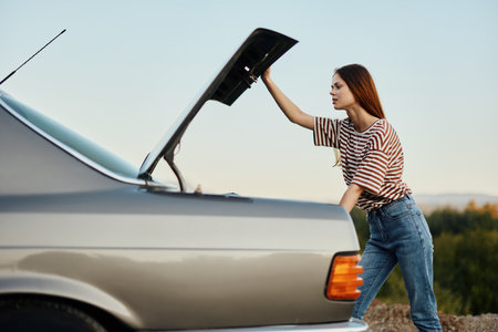The woman driver of the car opened the trunk with looks. Car breakdown while traveling on the road....