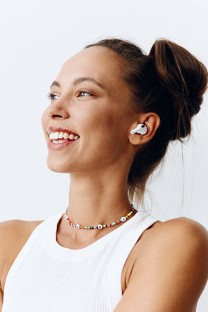 Woman with tanned skin portrait listening to music and audio on wireless headphones and smiling with her teeth on a white background. Technology and lifestyleの写真素材