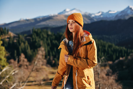 Woman hiking in the mountains in the fall with a smile with teeth and happiness in a yellow cape...