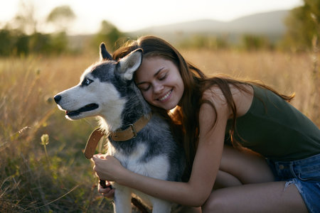 Woman smiling and hugging her dog sitting in a field with a dachshund dog smiling while spending time outdoors with a friend dog in autumn at sunset while travelingの写真素材