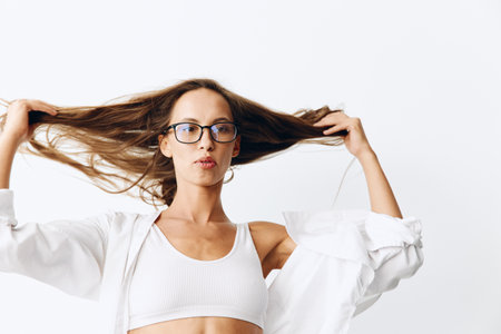 Beautiful female fashion model with tanned skin and long natural flowing hair posing on a white...