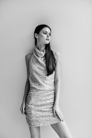 Young slender woman in gold glittery dress with open back poses, disco party image Christmas bow black and white photoの写真素材