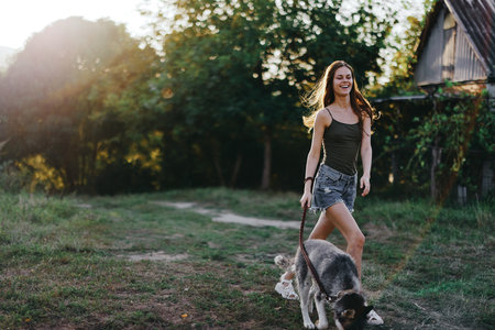 Woman and her husky dog happily running through the grass in nature in the park smile with teeth fall walk with pet, traveling with a dog friendの写真素材