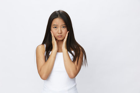 Asian woman hand signals, finger pointing facial skin problems, acne and inflammation, red rash and allergies, chicken pox, sadness from rashes. Facial skin care concept for diseases and nervesの写真素材