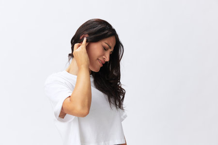 Woman toothache and sadness, inflammation of the teeth, a cold in a white t-shirt on a white backgroundの写真素材