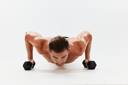 Man athletic body bodybuilder posing with dumbbells with naked torso abs full-length in the...