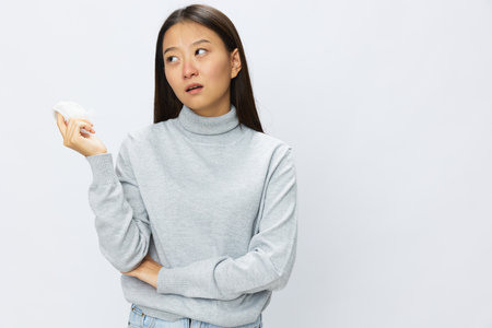 Sad Asian woman holding hand with handkerchief and coughing up flu and cold, stuffy nose viral...
